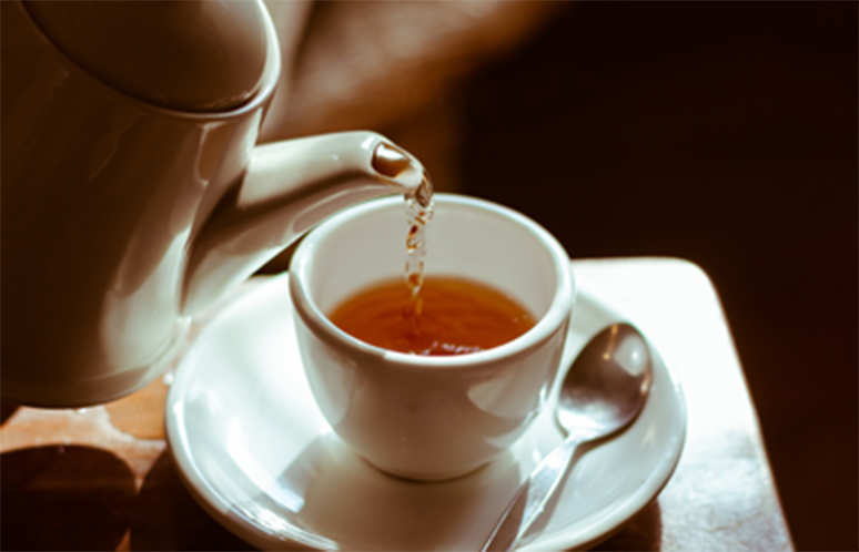 Pouring hot tea into white ceramic tea cup the time of tea break.